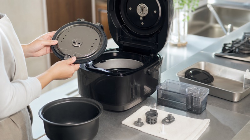 蒸気レス炊飯器のタンクや内ぶたを外して手入れを確認しているイメージ