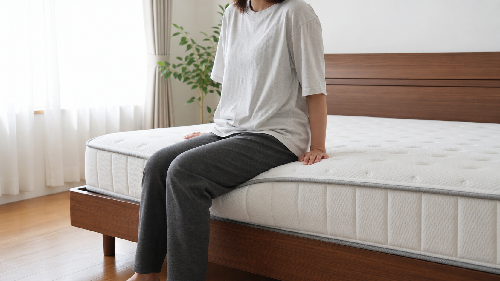ポケットコイルマットレスの端に座って沈み込みを確認する様子